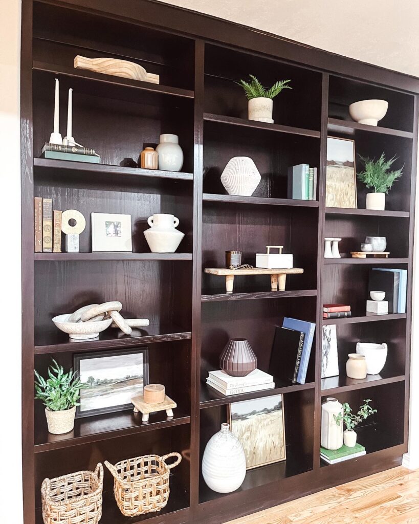Large dark wooden built in bookshelves with various decorative items.