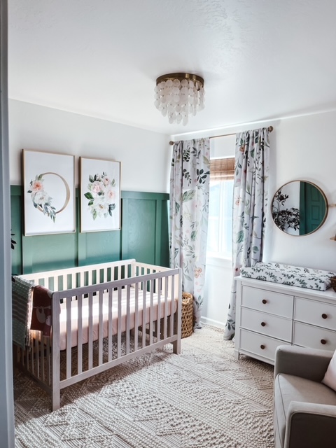 Cozy nursery room with a crib, floral artworks, and a changing station